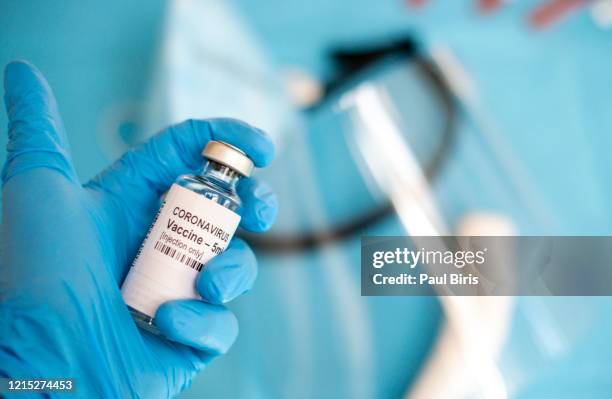 a doctor's hand with a syringe of covid-19 coronavirus vaccine. - crime or recreational drug or prison or legal trial fotografías e imágenes de stock