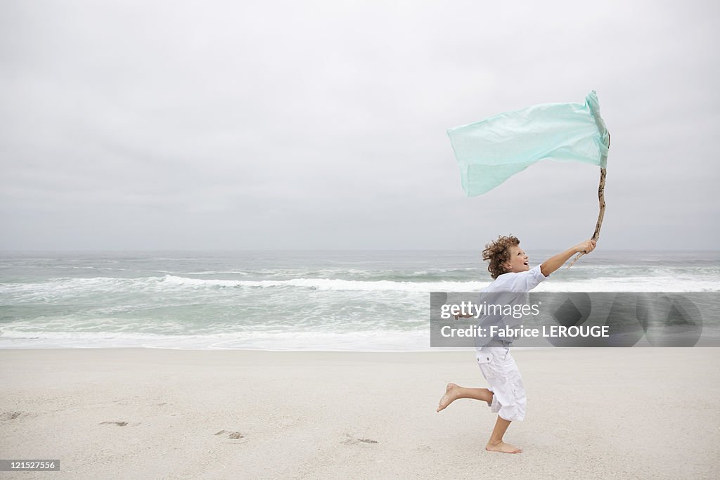 Boy running while holding flag on beach