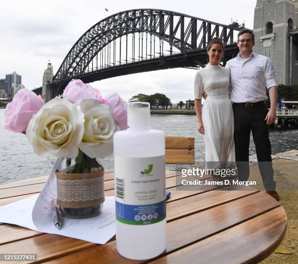 Posing for photos next to their hand sanitiser sat on the wedding table signing table, Lara Laas and Daniel Clark are married at Captain Henry...