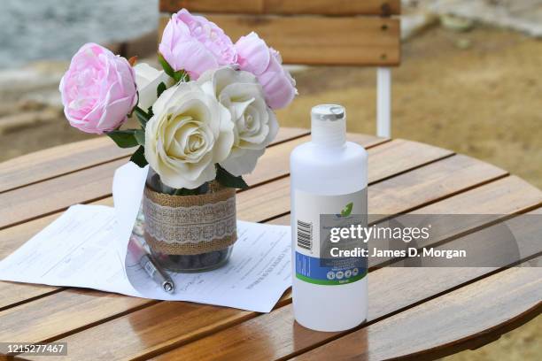 Hospital grade instant hand sanitiser sits next to some flowers as Lara Laas and Daniel Clark are married at Captain Henry Waterhouse Reserve in...