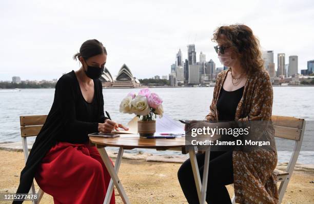 The two witnesses sign paperwork on a table beside the harbour for Lara Laas and Daniel Clark as they are married at Captain Henry Waterhouse Reserve...