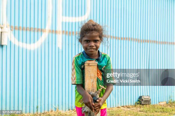 portrait of a young indigenous girl with curly hair standing at a water tap - australian aboriginal children stock pictures, royalty-free photos & images