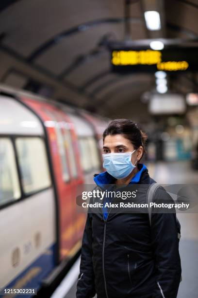 woman wearing a mask on the london subway or tube - london pollution stockfoto's en -beelden