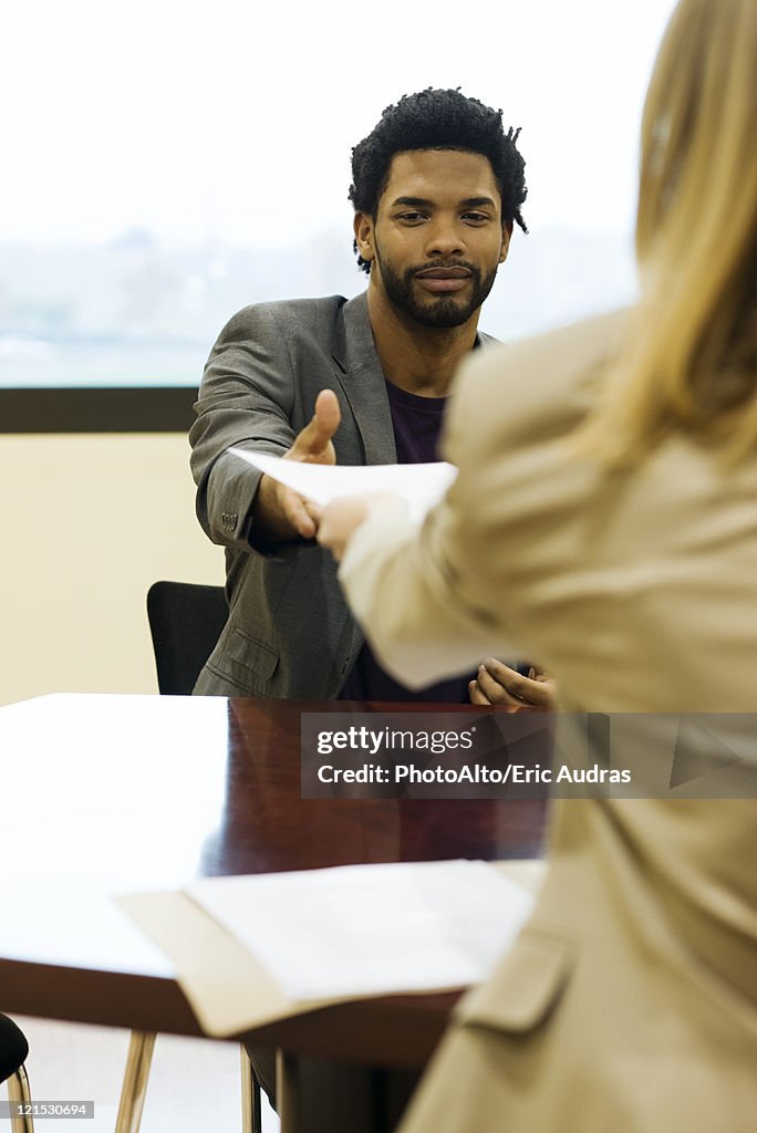 Man handing prospective employer his resume during job interview