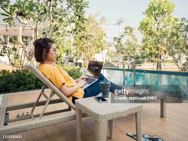 asian women using a laptop sitting near pool in summer - time off work stock pictures, royalty-free photos & images