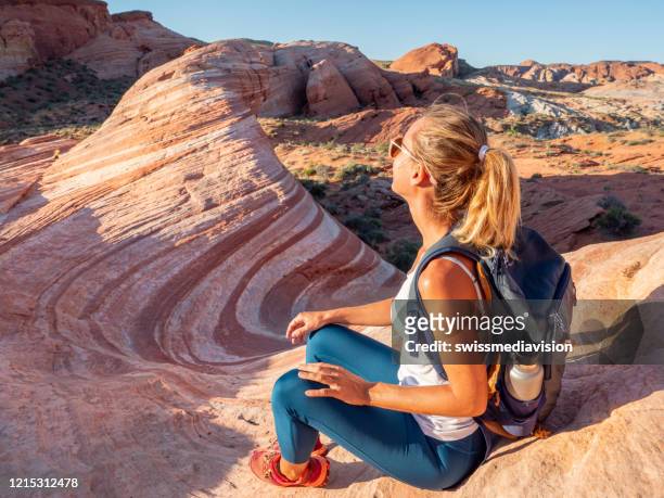 wanderfrau erwägt roten sandstein - valley of fire staatspark stock-fotos und bilder