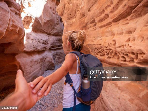 follow me, woman leading person to slot canyon hiking together and discovering new places - nevada hiking stock pictures, royalty-free photos & images