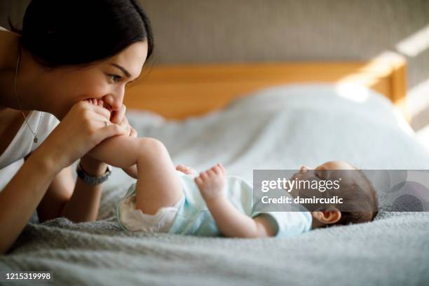 happy mother playing with her baby - foot kiss stock pictures, royalty-free photos & images