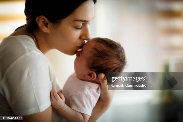 mutter küsst ihr weinendes baby - baby depression stock-fotos und bilder