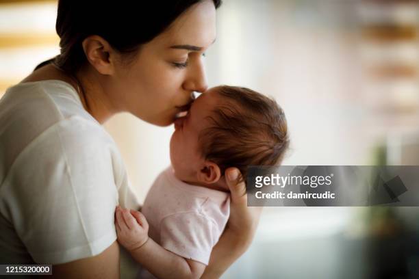 madre besando a su bebé llorando - baby depression fotografías e imágenes de stock