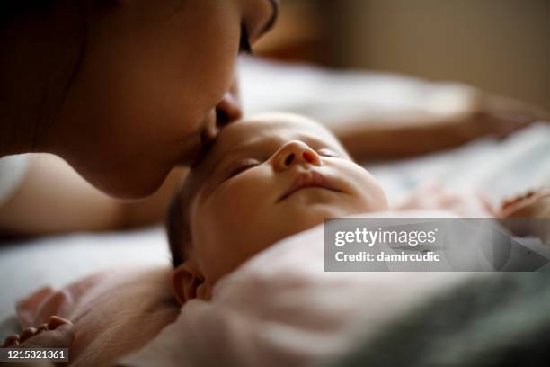 madre besando a su bebé recién nacido dormido - baby skin fotografías e imágenes de stock