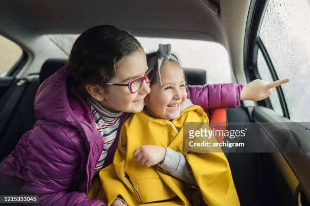zwei entzückende schwestern, die mit dem auto reisen - winter car window stock-fotos und bilder
