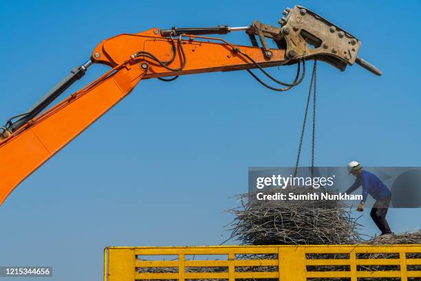 backhoe loading rebar scrap on the truck from demolish building in the construction site - rebuilding stock pictures, royalty-free photos & images