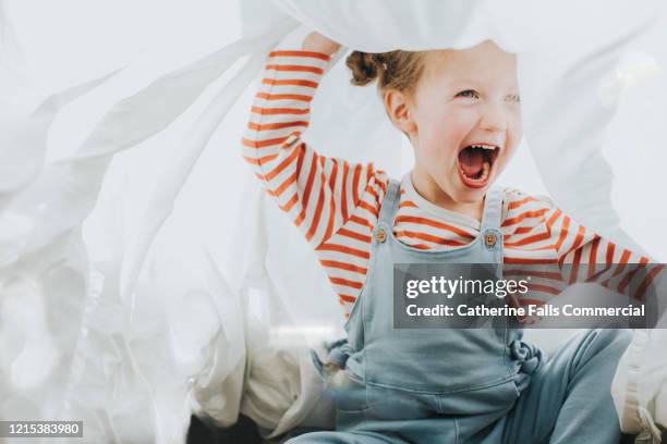 playful girl under a white sheet - wasmiddel stockfoto's en -beelden