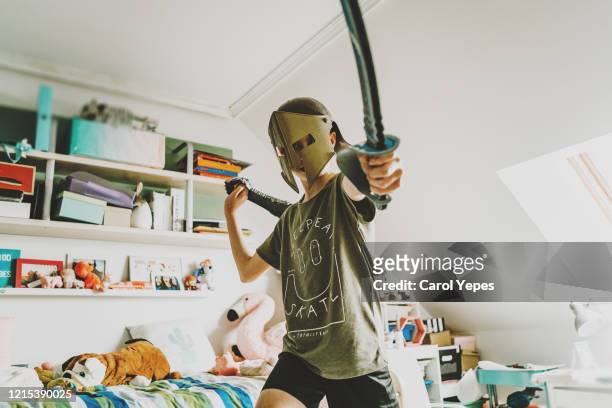 plauyful boy in his bedroom with warrior costume - ritter spielzeug stock-fotos und bilder