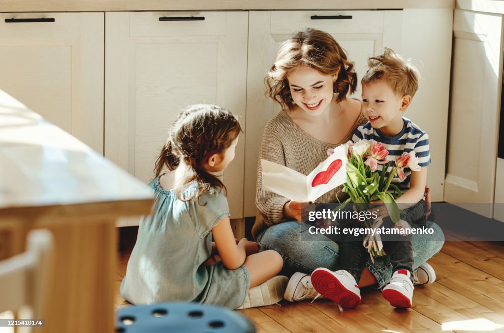 Happy mother getting gifts from kids at home