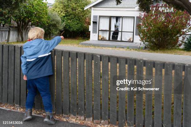 Teddy bear is seen in a window as a boy, who is the photographer's son, passes by on March 29, 2020 in Christchurch, New Zealand. Inspired by the...