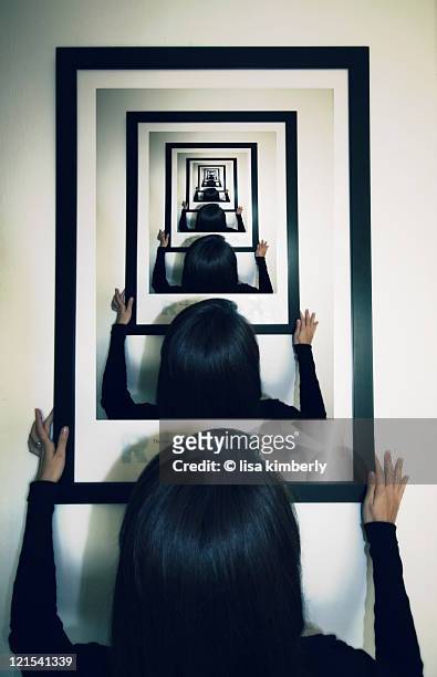 woman hanging photo on wall with droste effect - repetition foto e immagini stock