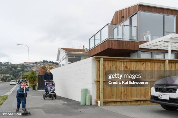 Teddy bear is seen in a window as a mother and her children, who are the photographer's family, pass by on March 29, 2020 in Christchurch, New...