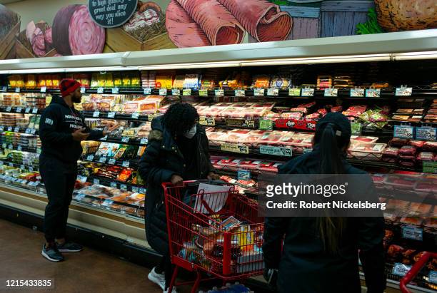 Shopper wearing a surgical mask, center, looks at looks at packaged meats at a Trader Joes in Brooklyn, New York on March 28, 2020. The store lets in...