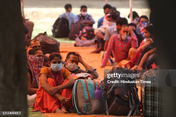Migrants from Jharkhand wait underneath a tent at Tau Devi Lal Stadium for transit buses to Faridabad where they were to board a Shramik Special...