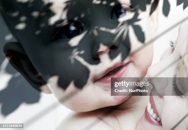 Shadows of a horsetree leaves is seen on the faces of a baby and a woman pictured on the advertisement of BioTexCom clinic next to its HQs in Kyiv,...