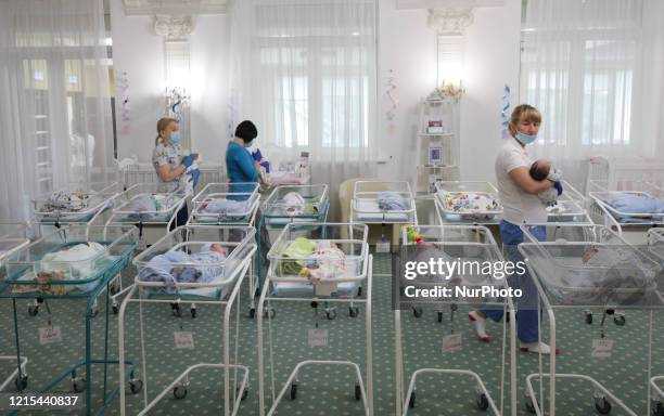 Babysitters put the babies back to their cradles after the feeding in a room inside Venice hotel owned by BioTexCom clinic in Kyiv, Ukraine, May 19,...