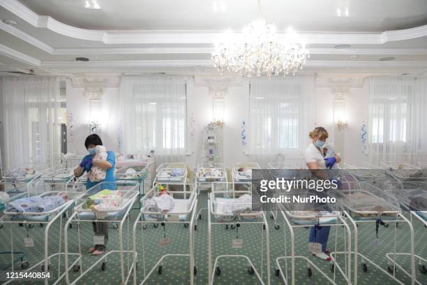 Babysitters carry the babies back to their cradles after the feeding in a room inside Venice hotel owned by BioTexCom clinic in Kyiv, Ukraine, May...