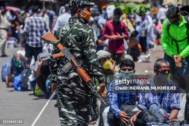 Central Industrial Security Force personnel patrols among migrant workers and families as they wait outside Dharavi slums for transportation to a...