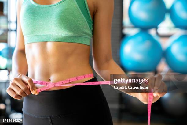 woman wearing fitness clothing  and measuring tape in the fitness room. healthy exercise concepts - fat loss stock-fotos und bilder