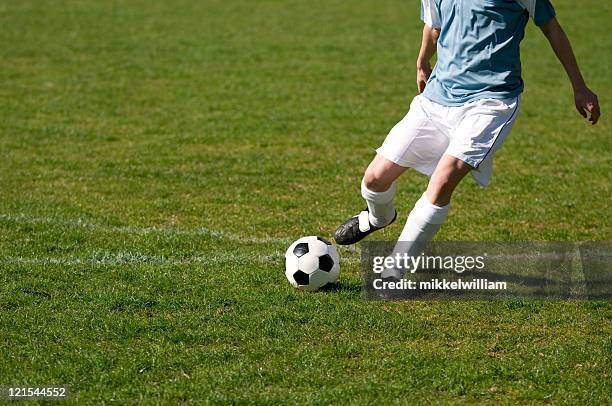 football player shoots soccer ball on a field - passing stock pictures, royalty-free photos & images