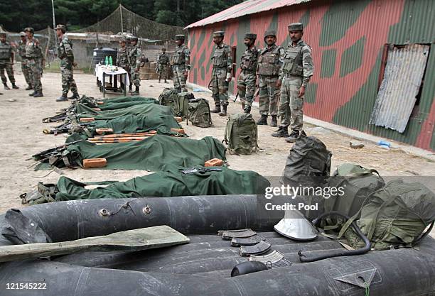 Indian Army soldiers stand guard in front the ammunition, dinghy and bodies of suspected militants killed by Indian Army on August 20, 2011 in Gurez,...