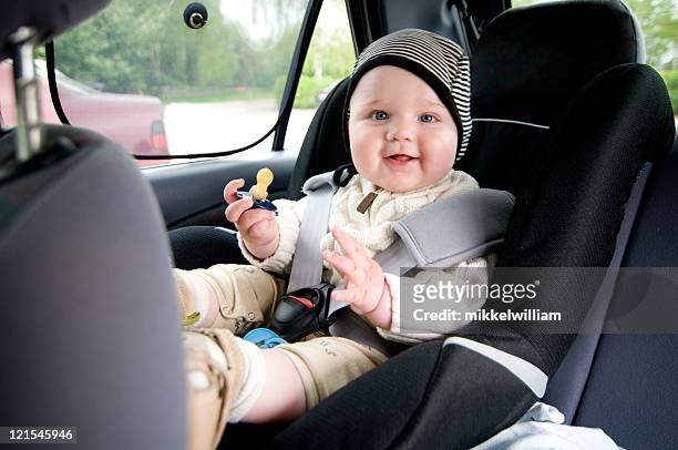 a baby front facing early in car seat and unsafely strapped - baby car seat stock pictures, royalty-free photos & images