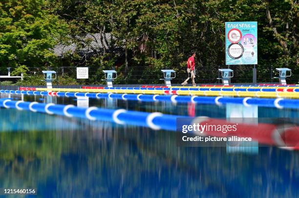 May 2020, Brandenburg, Kleinmachnow: The swimming champion walks past the sports pool and the sign "Badespaß" in the open-air pool in Kiebitzberge....