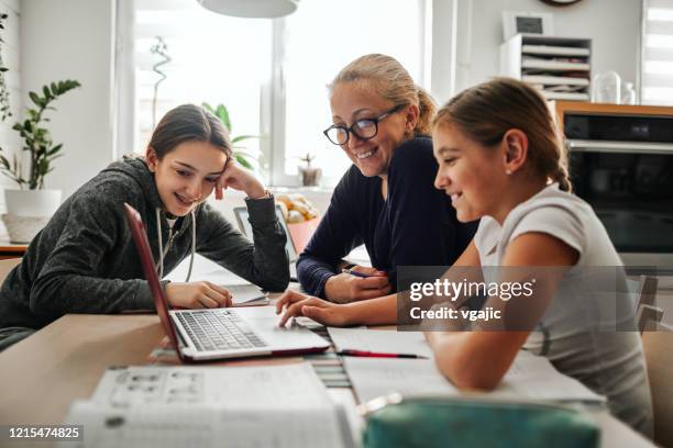 homeschooling - mother helping to her daughters to finish school homework during coronavirus quarantine - homeschooling computer stock pictures, royalty-free photos & images