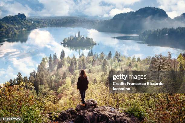 woman watching sunrise over bled lake, slovenia, europe. - lake bled stockfoto's en -beelden