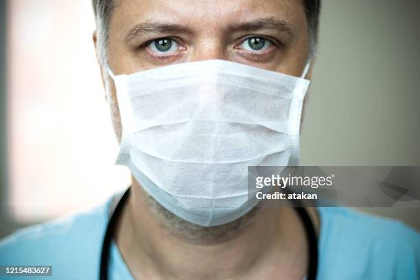 médecin aux yeux verts d’âge moyen de plan rapproché avec le masque sur son visage - face mask coronavirus photos et images de collection