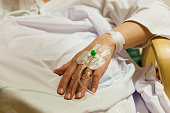 Female patient in hospital getting treatment by peripheral intravenous transfusion catheter. Real people closeup of hand and arm.