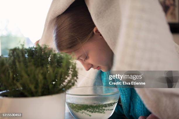 teenager using herbal steam inhalation as a remedy to treat respiratory symptoms of cold and flu virus - medicina alternativa foto e immagini stock