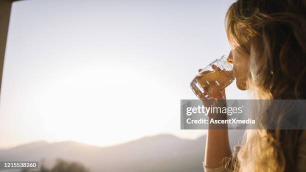 junge frau entspannt auf der terrasse - glass water stock-fotos und bilder