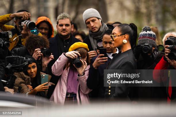 Jourdan Dunn wears golden earrings, sunglasses, a black jacket and poses in front of photographers, outside Balmain, during Paris Fashion Week -...