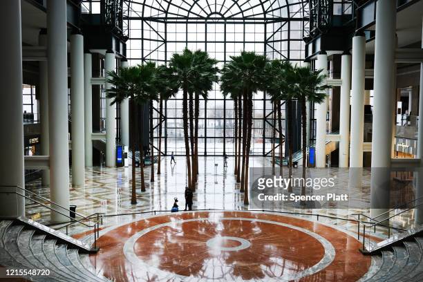 People walk through an empty Brookfield Place mall in lower Manhattan on March 29, 2020 in New York City. Across the country schools, businesses and...