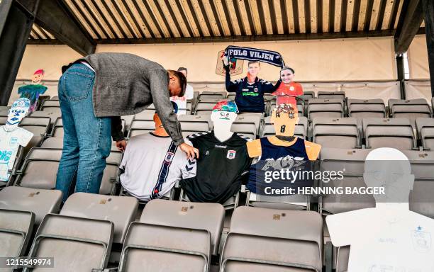 Man places cardboard figures with pictures of the fans in the empty tribunes of the Ceres Park Football Stadium on the eve of the Danish Superliga...