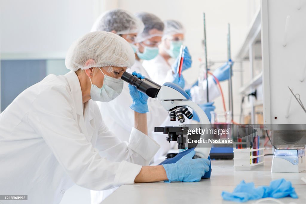 Scientists studying a virus ,looking through microscope