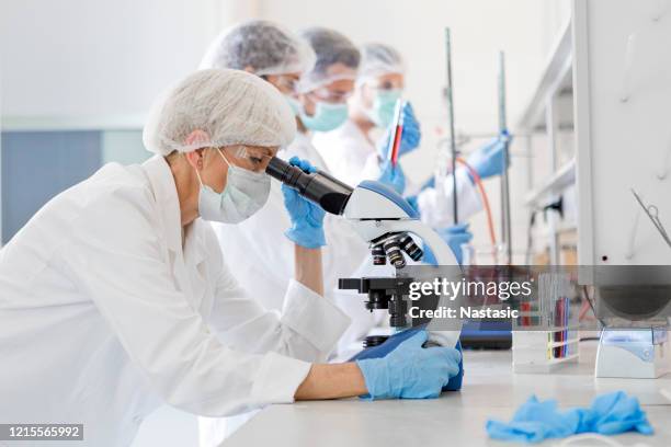 scientists studying a virus ,looking through microscope - ensaio imagens e fotografias de stock