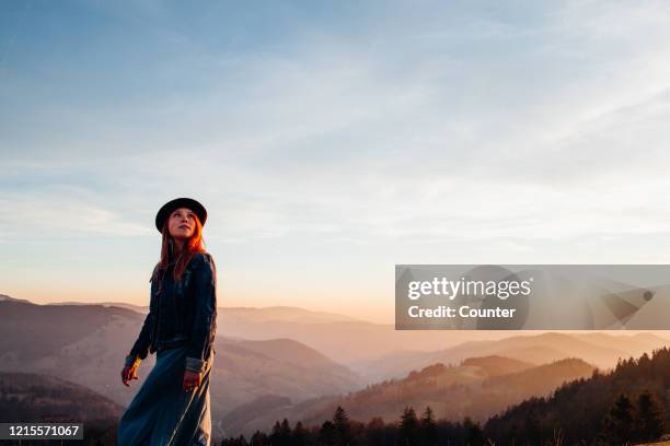 young woman with hat on mountain at sunset - explore freedom stock-fotos und bilder