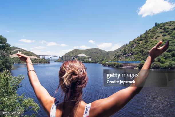 a woman raising arms in happiness against beautiful lake - córdoba argentina stock pictures, royalty-free photos & images