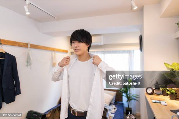 junger mann trägt morgens hemden - anziehen stock-fotos und bilder