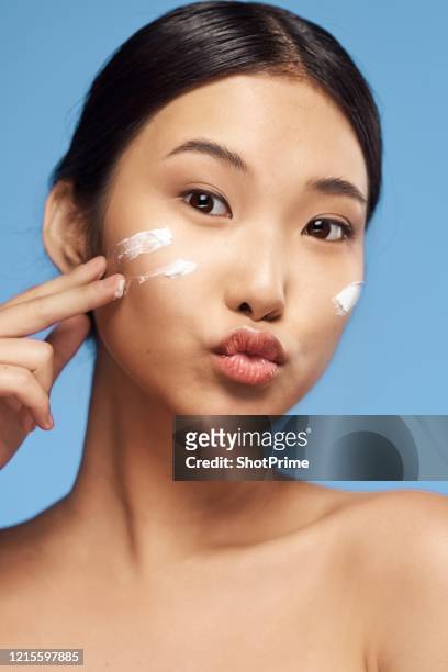 beauty portrait of a young asian woman with clean and healthy skin who applies cream to her face. - korea imagens e fotografias de stock