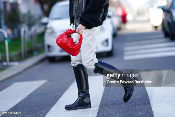 Guest wears rings, a black leather jacket with black suede sleeves , white leather pants, black riding boots, a red woven leather handbag, outside...